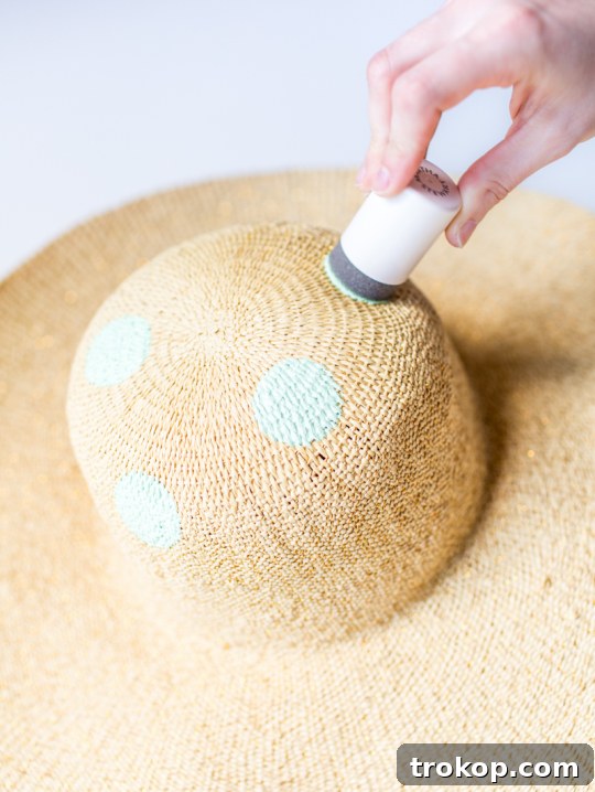 Stylish DIY Polka Dot Floppy Hat 5 Detailed shot of dipping a foam pouncer into craft paint for a DIY polka dot hat project, showing preparation.