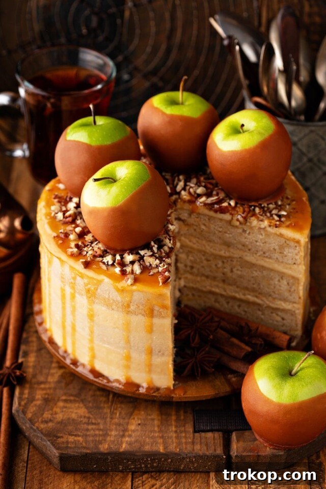Decadent salted caramel apple cake with spiced layers, fluffy buttercream, and caramel drizzle, topped with apples and pecans.