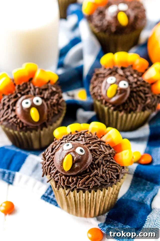 Festive turkey cupcakes decorated with colorful frosting, sprinkles, M&M's, candy eyes, and candy corn, both adorable and delicious.