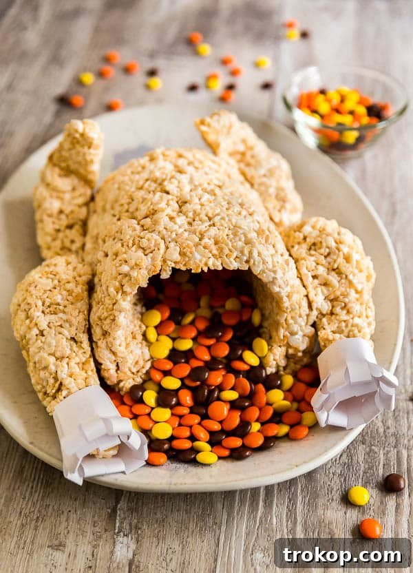 A festive Rice Krispie Treats turkey adorned with chocolate candy, a fun no-bake Thanksgiving dessert idea for kids.