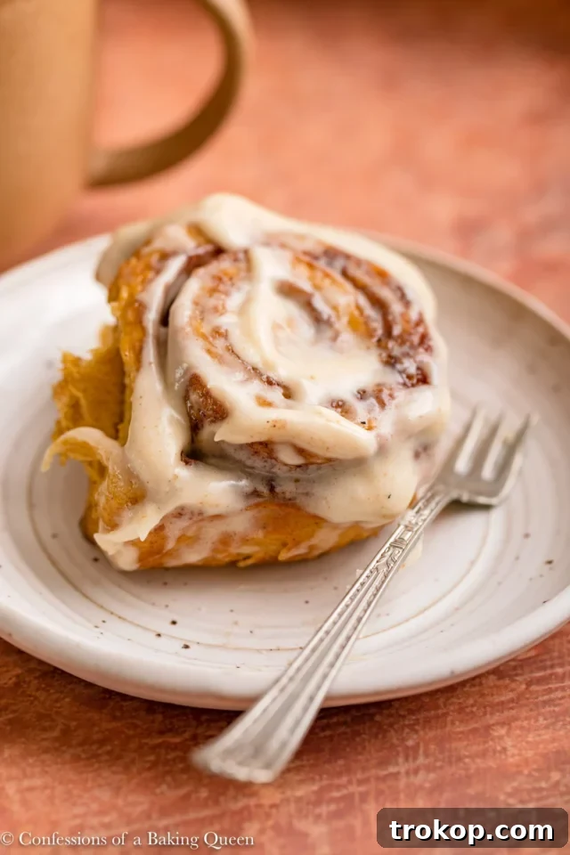 Fluffy pumpkin cinnamon rolls swirled with pumpkin filling and topped with creamy cream cheese glaze, perfect for a sweet Thanksgiving breakfast or dessert.