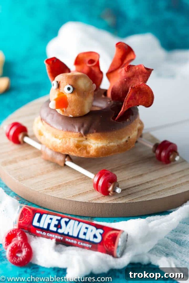A playful Thanksgiving treat: a donut transformed into a turkey race car with candy wheels and a cute turkey topper, fun for kids.