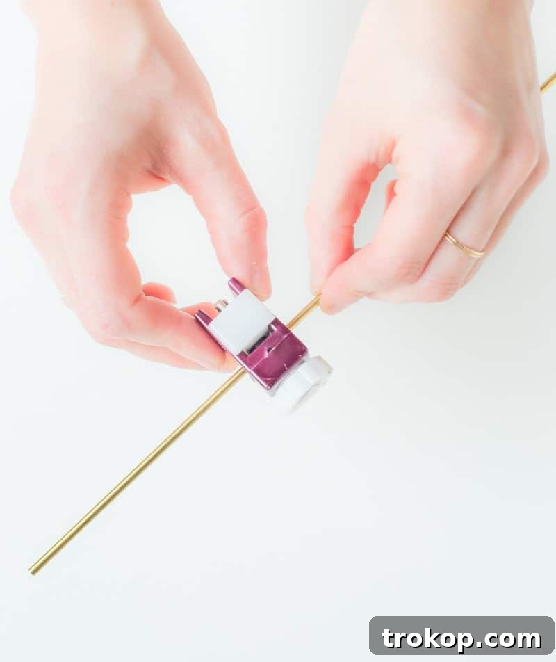 Measuring a brass tube against a cocktail glass to determine optimal length for DIY stirrers