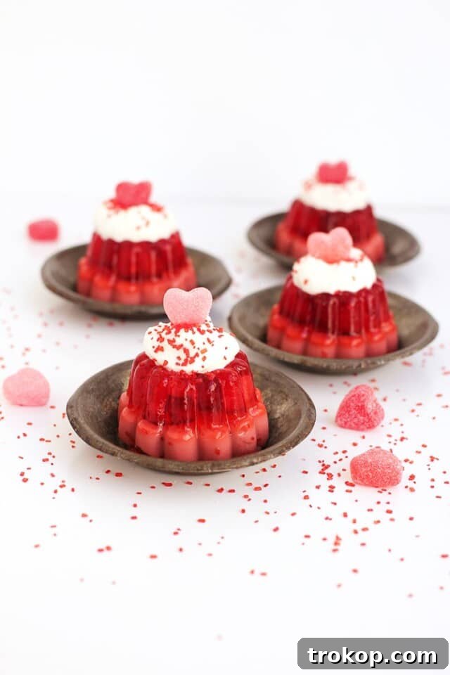 34 Irresistible Valentine's Day Treats 20 Adorable mini Valentine's Jello molds, layered with cherry cream and raspberry jello, topped with whipped cream, evoking vintage charm and delightful flavor.