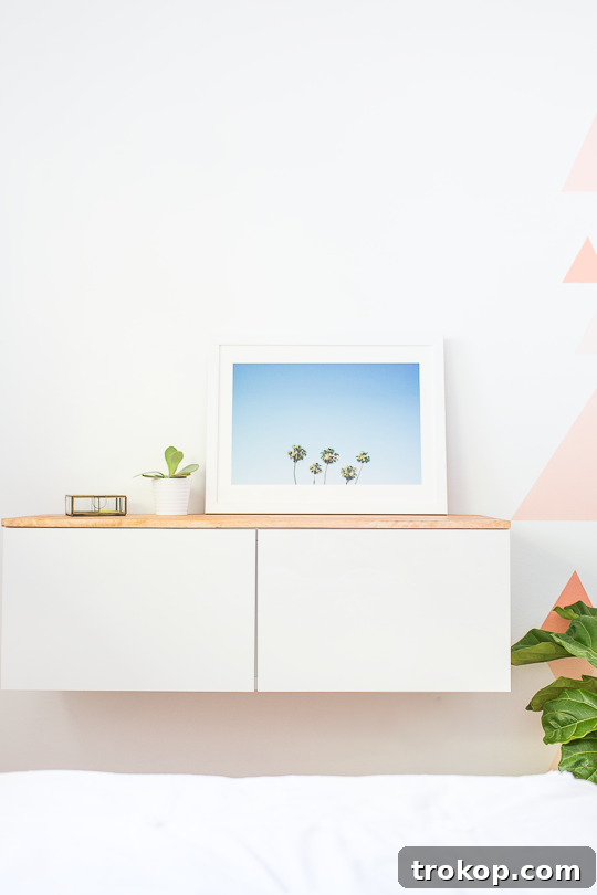 Close-up of styled DIY IKEA floating credenza with a palm tree print, succulent, and gold box.