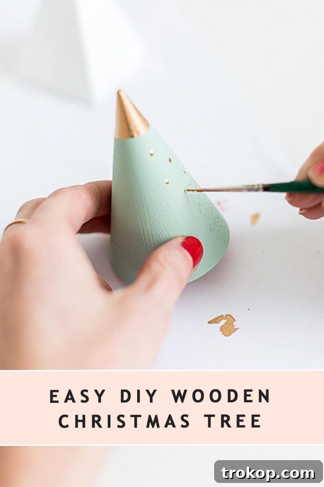 Photo of painting a tree shaped wooden cone for christmas by sugar and cloth