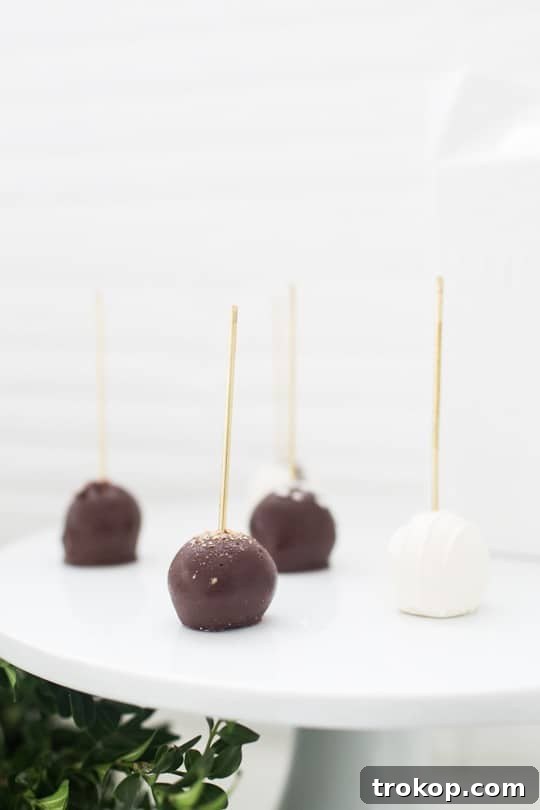 Elegant brass food picks serving truffles and cake pops on a dessert table.
