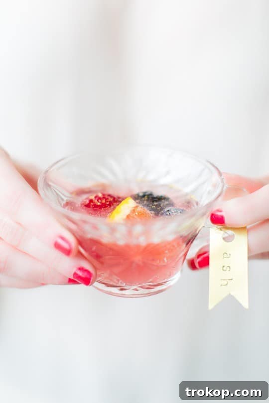 Berry Punch Perfection DIY Brass Drink Markers 11 A close-up of a glass filled with Mixed Berry Punch, adorned with fresh berry garnishes and a charming brass drink tag.