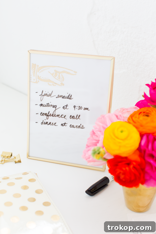 Craft Your Own Erasable Canvas 5 Materials laid out for making a DIY Desktop Dry Erase Board, including a gold frame, white paper, and a gold pen.