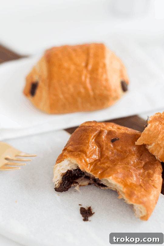 Two-Ingredient Chocolate Croissant Magic 5 Four chocolate croissants cooling on a wire rack, freshly baked.