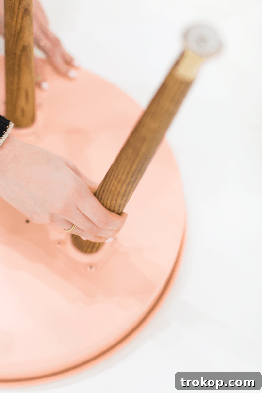 Securing the angled leg mounting plates to the cake pan with screws and nuts.