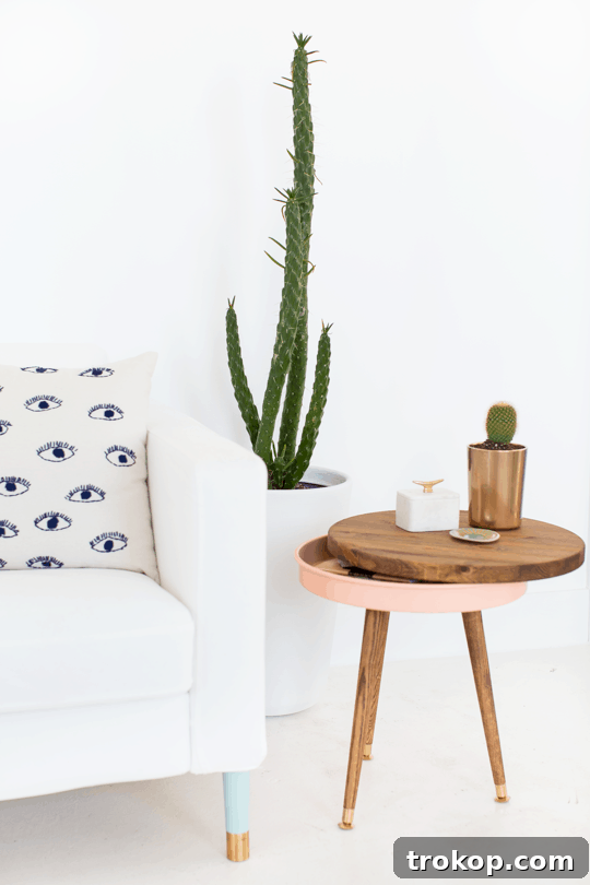 Completed DIY Mid Century Modern Side Table with a pink storage base and dark wood top, styled with home decor items.