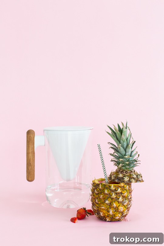 5 Refreshing Infused Water Recipes & DIY Fruit Cups 13 A glass of refreshing fruit-infused water with colorful garnishes and striped straws