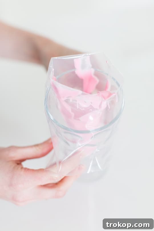 Piping melted pink chocolate into elegant 'S' shapes on wax paper for flamingo heads