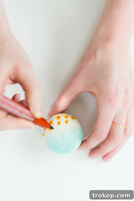Decorating beach macarons with edible markers for umbrellas and people