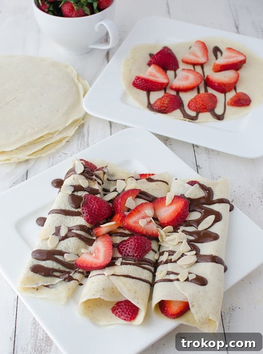 Strawberry Almond Crepes with Decadent Chocolate Drizzle 2 Delicious strawberry almond crepes with chocolate sauce, ready to be enjoyed