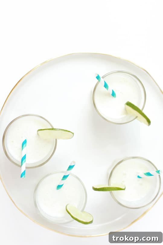 Spiked Brazilian Limeade Served Over Ice - A refreshing glass of the creamy cocktail, garnished with a lime wheel.