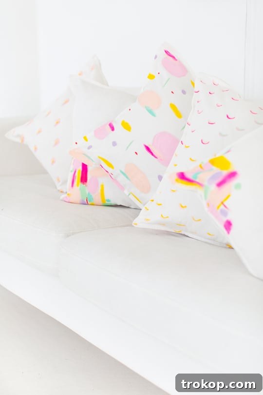 Arrangement of paint brushes, fabric paints, and a white pillow cover