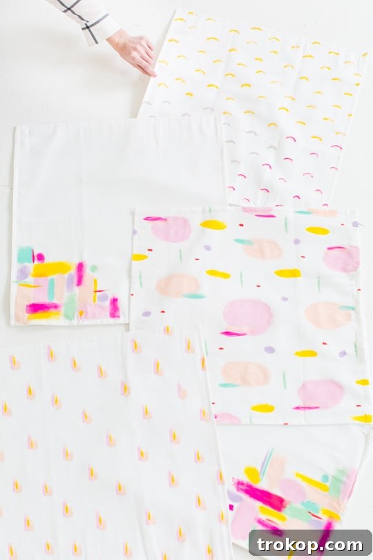 Multiple newly painted DIY throw pillow covers laid out to dry