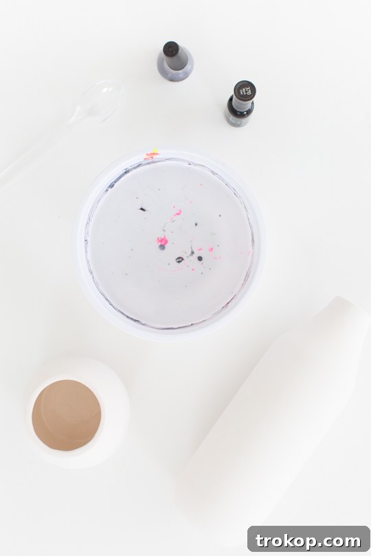 Materials laid out for DIY marble dipping, including nail polish, ceramic vessels, and a plastic bowl with water.