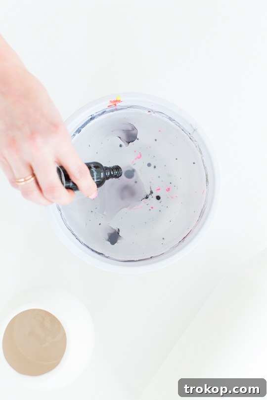 Step-by-step image showing nail polish being dropped into warm water in a plastic bowl for marbling.