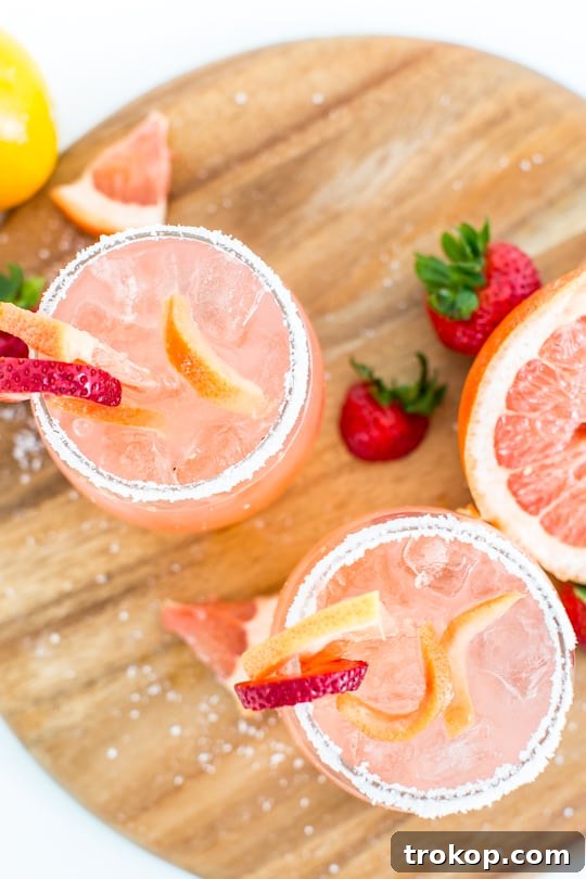 Close-up of a Strawberry Grapefruit Salty Dog cocktail garnished with a grapefruit slice and strawberry.