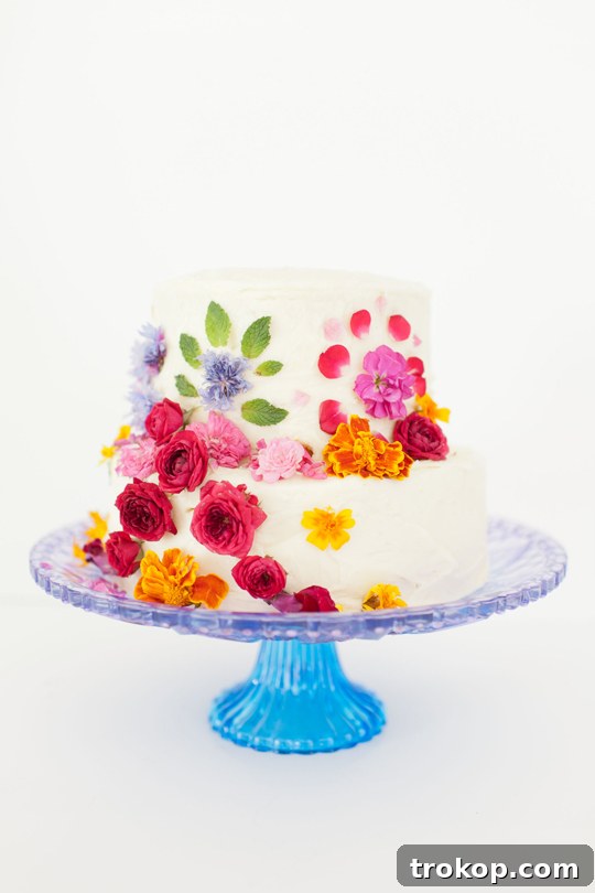 Two-tiered cake decorated with edible flowers and fresh herbs