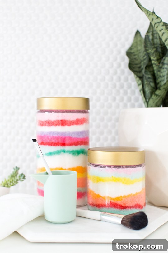 Rainbow Layered Sugar Scrub Craft 11 A top-down view of a clear glass jar filled with Sand Art DIY Sugar Scrub, showing intricate layers of blue, green, and pink colors, with a handwritten tag 'Sugar & Cloth'.