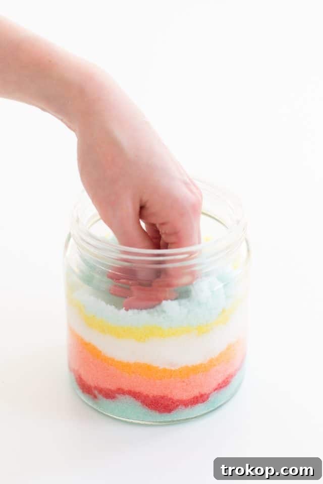 Rainbow Layered Sugar Scrub Craft 8 A close-up of a glass jar filled with multiple layers of different colored sugar scrub, showcasing the intricate patterns achieved through the sand art technique.