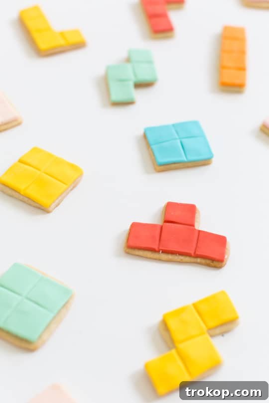 Pixel Perfect Tetris Bites 5 Four freshly baked Tetris cookies, one decorated with blue fondant, on a wooden board