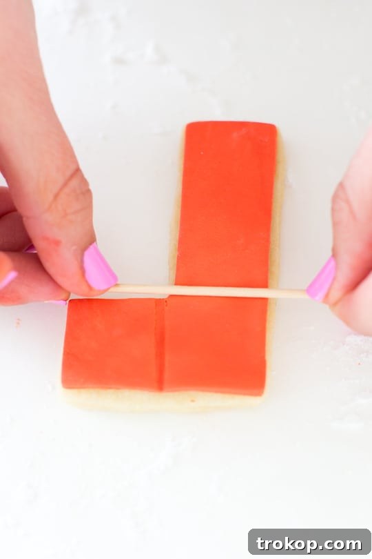 Pixel Perfect Tetris Bites 8 Hands using a mini wooden dowel to create square indentations on a fondant-decorated Tetris cookie