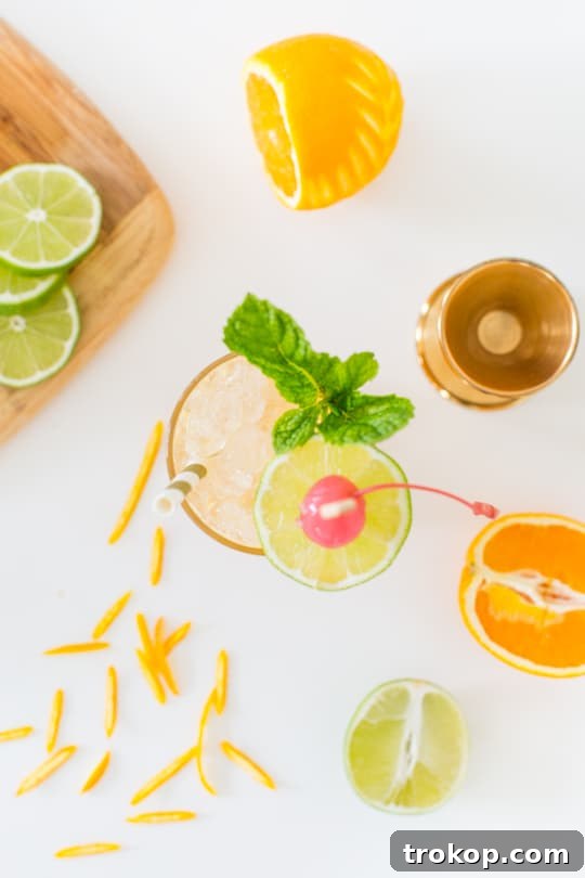 Expertly prepared Esmeralda Fizz cocktail with intricate orange peel garnish, ready to serve.