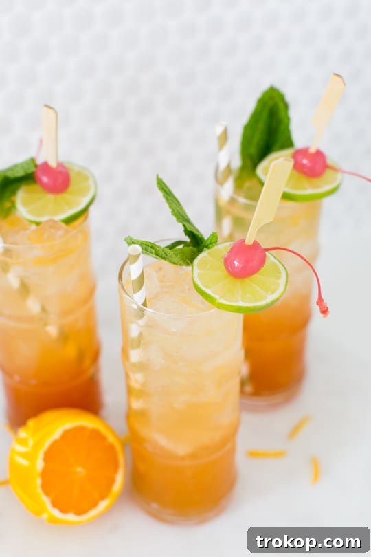 A close-up of the Esmeralda Fizz cocktail showing the artful orange peel garnish and vibrant color.