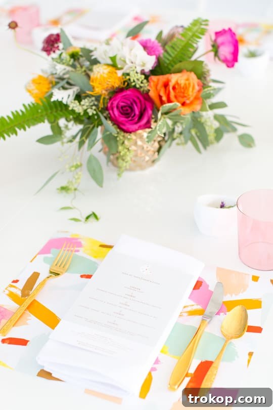 The Ultimate Sweet and Savory Dinner Party Guide 8 Beautifully arranged dinner table with brushstroke placemats, gold flatware, and fresh floral centerpieces