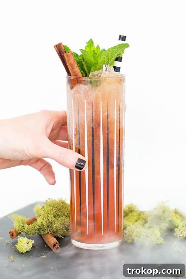 A hand holding a garnished Zombie cocktail glass, ready to be enjoyed.