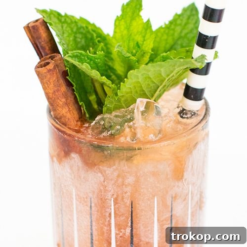 Close up photo of a Zombie cocktail over ice, garnished with mint and a cherry.