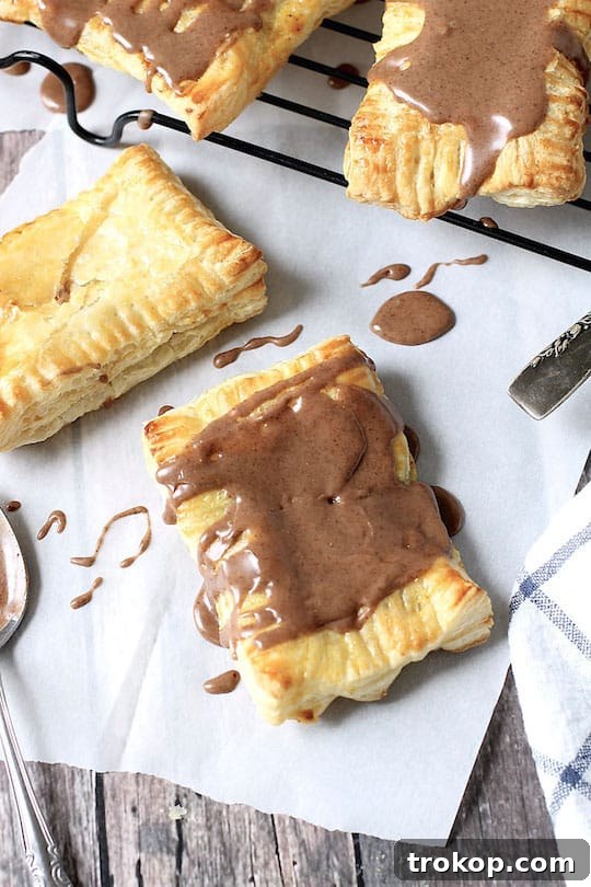 DIY Pumpkin Spice Toaster Pastries 3 Flaky Pumpkin Pie Pop Tarts with icing on a cooling rack.