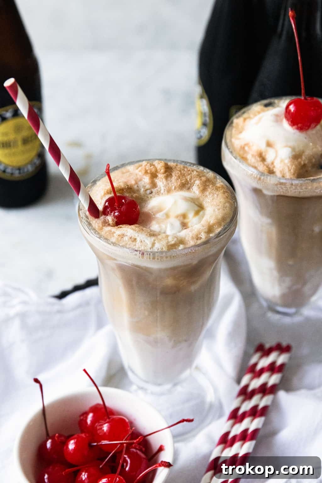 Close-up photo of a root beer float featuring two scoops of ice cream and a cherry on top, highlighting the creamy texture.