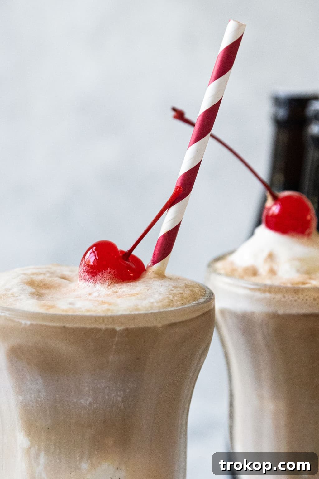 A close-up shot of a root beer float's creamy foam and rich dark liquid, emphasizing its delicious texture.