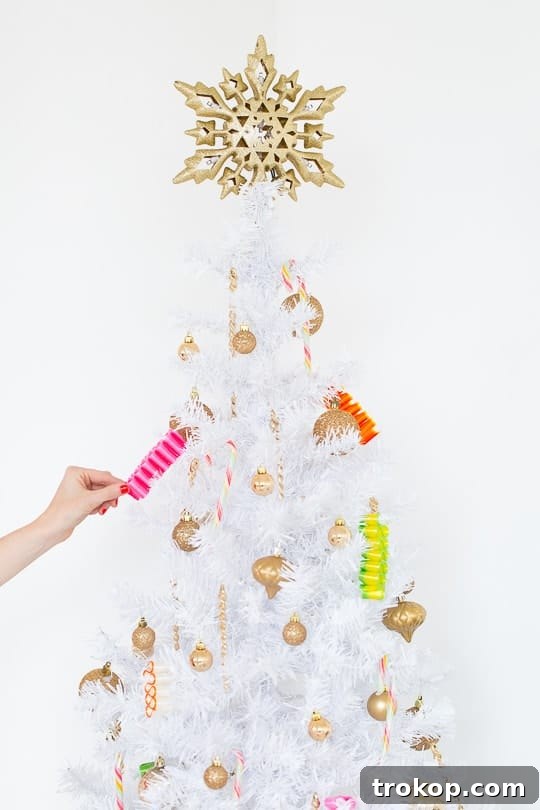 Close-up of a stylish white pre-lit Christmas tree adorned with gold accents and candy ribbon, a Walmart find.