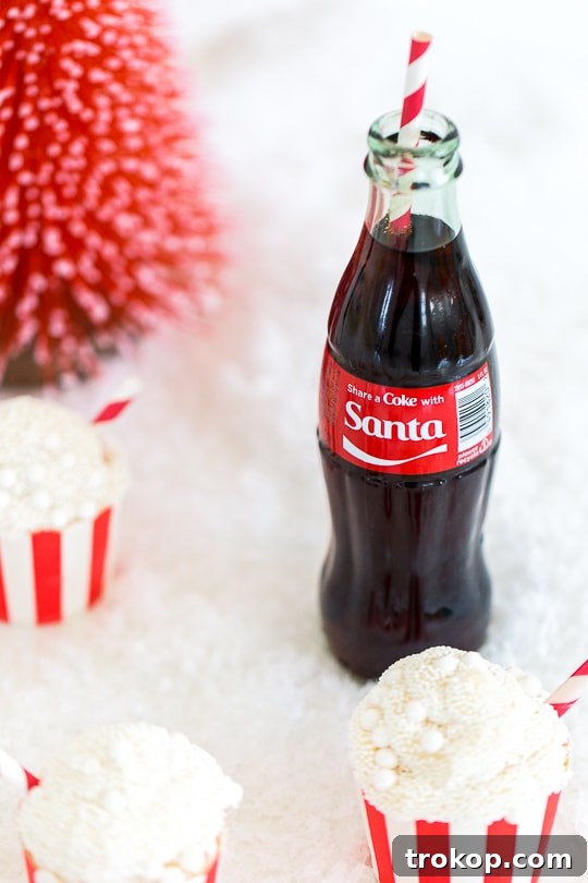 Old-Fashioned Coca-Cola Cupcakes 5 A refreshing glass of Coca-Cola soda with a straw, perfect pairing for the cupcakes