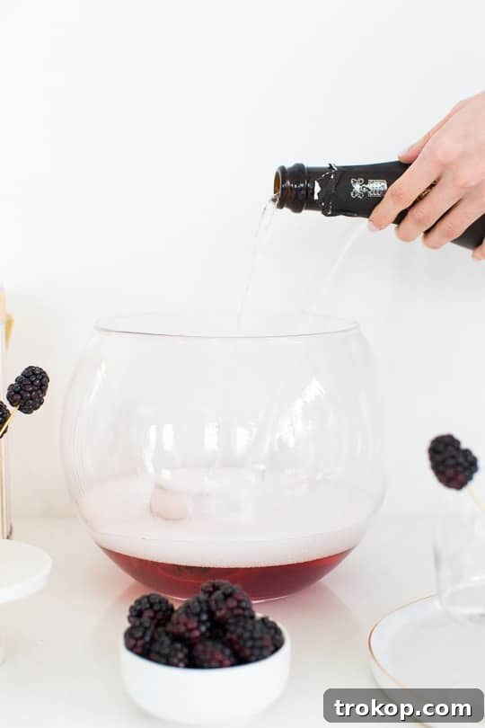 3-Ingredient Blackberry Champagne Fizz 6 Hand pouring IZZE Sparkling Blackberry Juice into a punch bowl