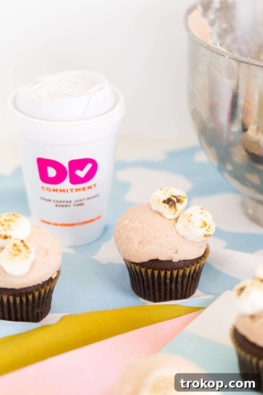Three Dunkin' Donuts Hot Chocolate Cupcakes beautifully arranged, showcasing the toasted marshmallow topping.