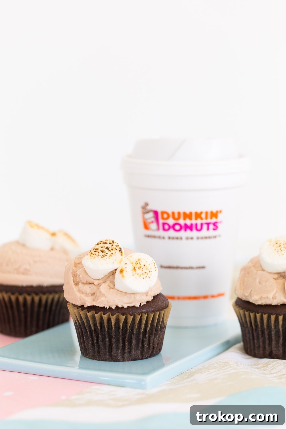 Overhead shot of freshly baked cupcakes waiting to be frosted with Dunkin' Donuts hot chocolate icing.