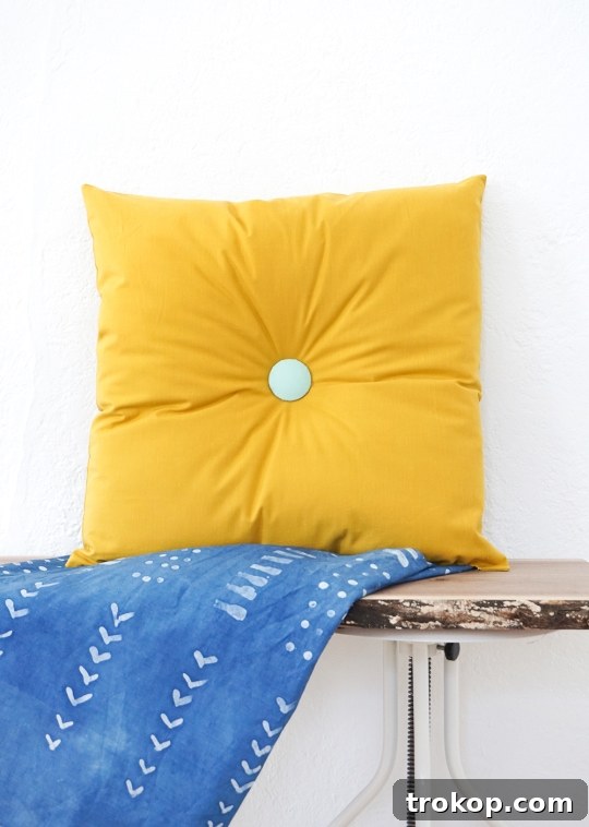Image of a completed yellow DIY tufted pillow on a sofa