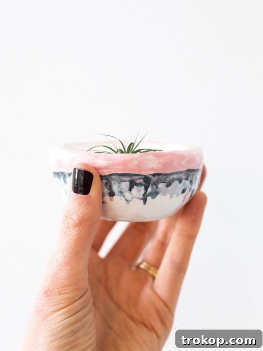 A trio of colorful mini DIY air plant pots on a rustic wooden board