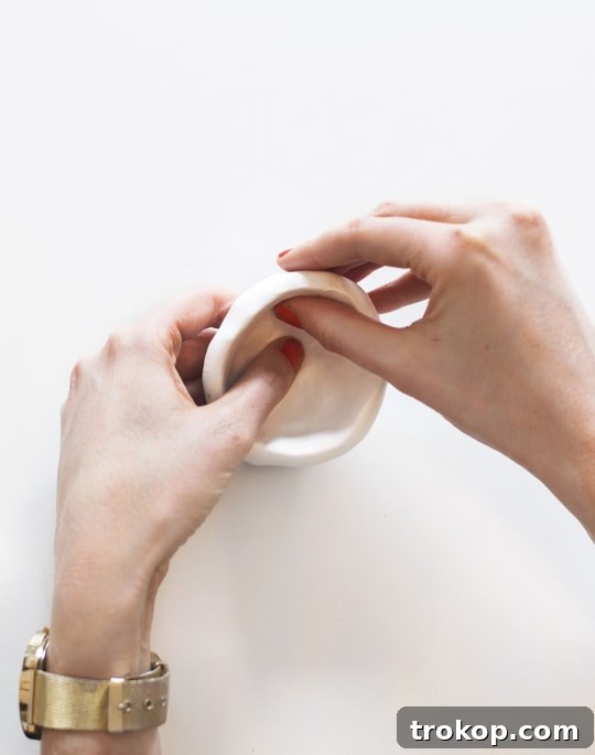 Flattening the rim of a polymer clay pinch pot on a smooth surface