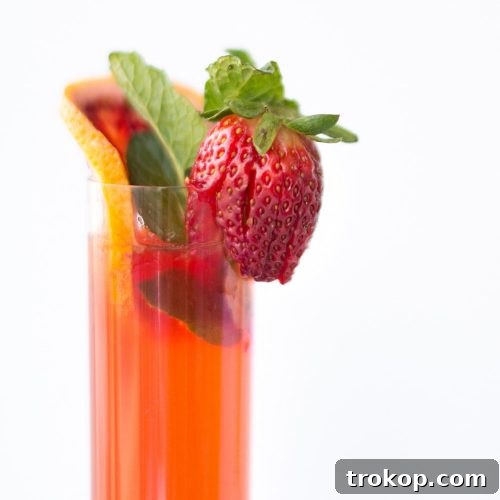 Sparkling Pimm's Cup cocktail garnished with cucumber, strawberry, and blood orange