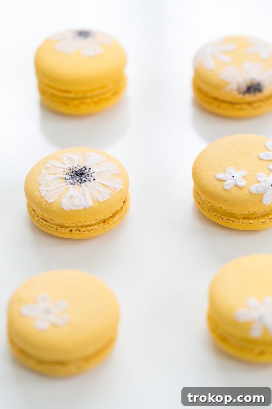 Multiple yellow macarons decorated with white daisy patterns