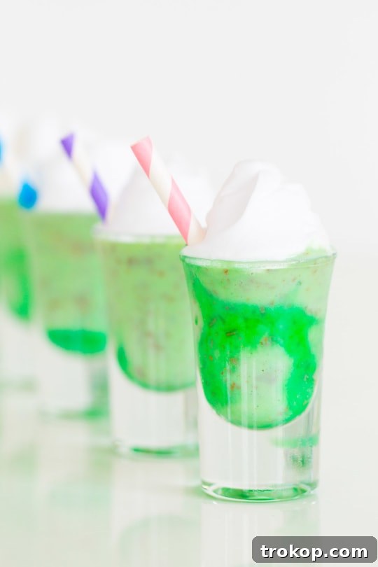 A close-up of a single Creme de Menthe Ice Cream Shot, showcasing the marbled green and white ice cream, topped with fresh whipped cream and chocolate shavings.